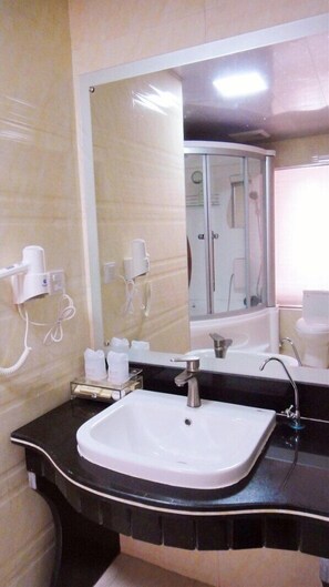 Bathroom features a large mirror, a single sink with a central faucet, and two wall-mounted hair dryers.
