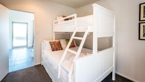 Habitación con literas, puerta a un balcón y un cuadro en la pared.