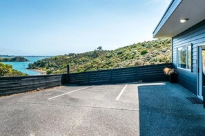 Un bâtiment moderne doté d’un patio en béton et offrant une vue sur un paysage côtier.
