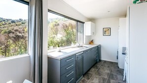 Una cocina moderna con un ventanal grande, armarios oscuros y vistas al exterior.
