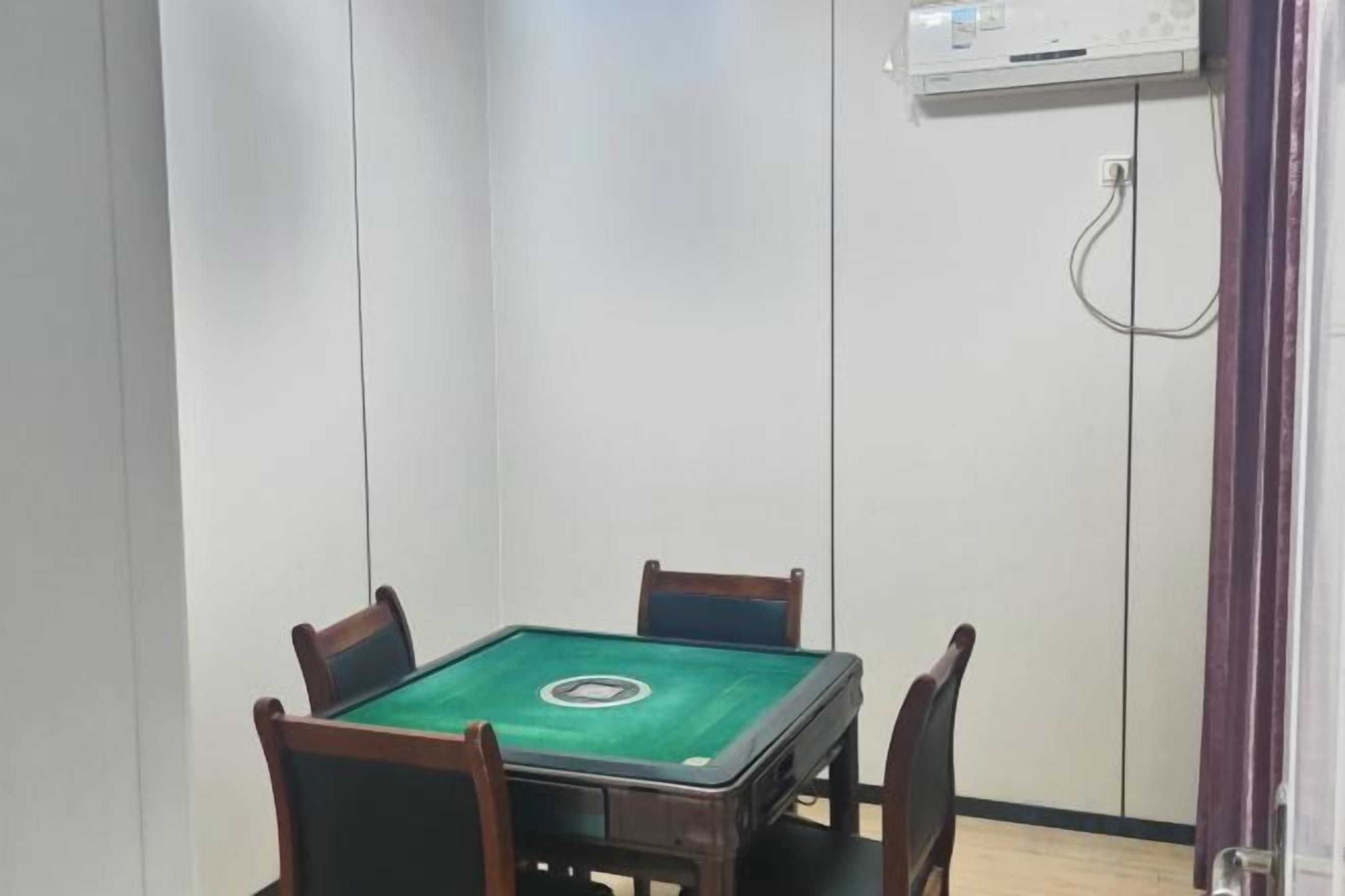 A room with a green pool table, four chairs, a white wall, and a door with a purple curtain.