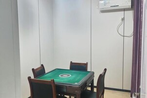 Una habitación con mesa de billar verde, cuatro sillas, una pared blanca y una puerta con cortina púrpura.