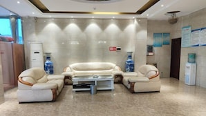Eine Lobby mit einer beigefarbenen Sofagarnitur, einem Couchtisch und einem Wasserspender.
