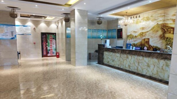 Ein Hotel-Empfangsbereich mit Marmorboden, einer Rezeption, einer Wand mit Wandgemälde und einem Feuerlöscher.