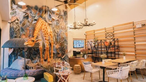 A restaurant with a giraffe mural, wooden slat walls, and a ceiling fan. - B Innspire Hotel (Chiang Mai)
