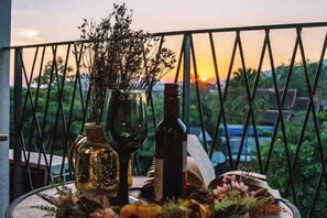 A table with a bottle, wine glass, and flowers on a balcony with a view of the sunset. - B Innspire Hotel (Chiang Mai)