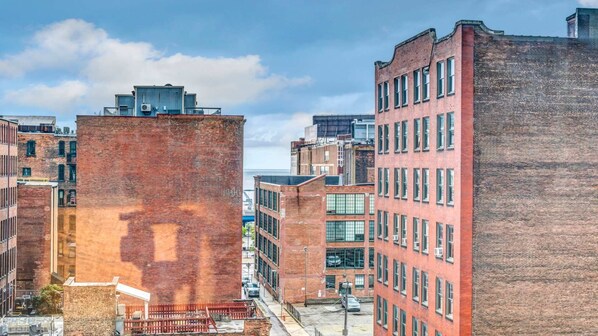 A row of multi-story brick buildings with large windows, a clear sky, and a visible street in the foreground.