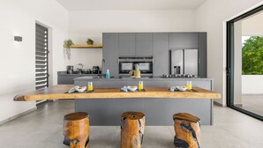 Una cocina moderna con una isla central, armarios grises y un amplio ventanal con vistas a zonas verdes.