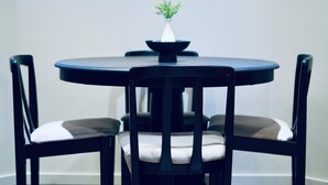 A round table with a black top and a white vase with a green plant. There are two black chairs with white cushions. - Entire suite Neighboring RCMP, Stadium and Airport. (Regina)