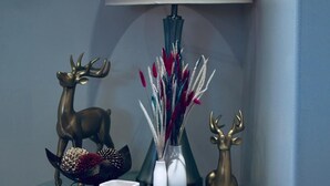 A glass table with a lamp, decorative items, and a small sculpture. - Entire suite Neighboring RCMP, Stadium and Airport. (Regina)