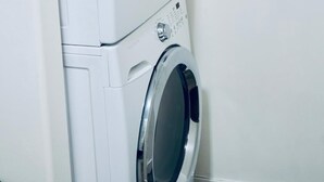 A front-loading washing machine and dryer stacked vertically in a laundry room. - Entire suite Neighboring RCMP, Stadium and Airport. (Regina)