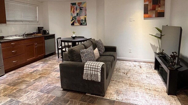 A compact living space with a sofa, a dining table, and a kitchen area. - Entire suite Neighboring RCMP, Stadium and Airport. (Regina)