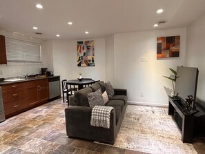 A compact living space with a sofa, a dining table, and a kitchen area. - Entire suite Neighboring RCMP, Stadium and Airport. (Regina)