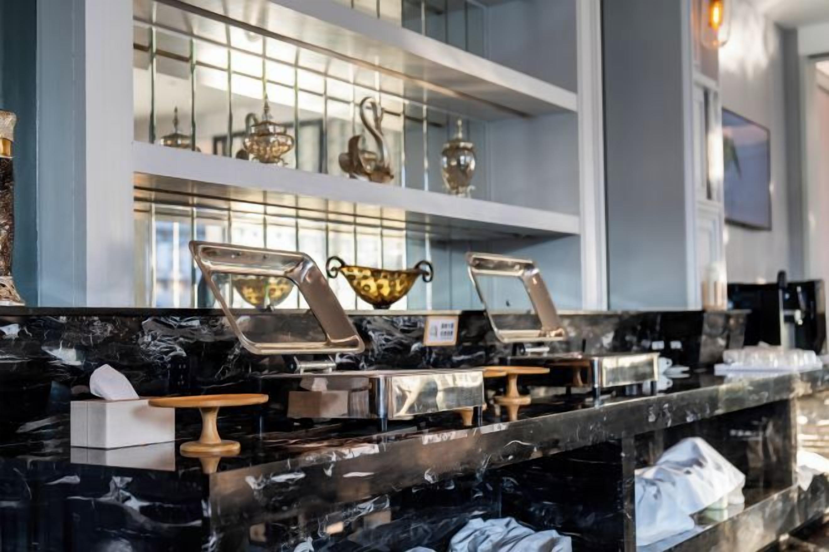 A marble countertop with multiple service stations, a glass display case, and a white shelf with decorative items.
