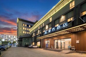 Un hotel con fachada moderna, varios pisos y una entrada bien iluminada.
