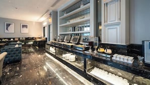Eine moderne Hotelhalle mit einem мраморнем Empfangsschalter, einer Sitzecke mit раптом Sofa und einer Glasvitrine mit verschiedenen Gegenständen.