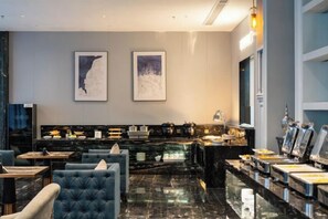 A modern hotel lobby with a marble reception desk, seating area, and artwork on the walls. - McQueen Hotel (Dongguan)