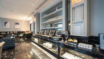 A hotel lobby with a marble reception desk, seating area, and a buffet with various food items.