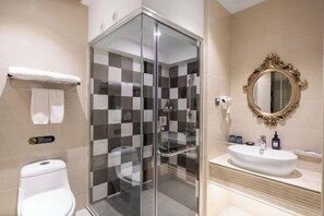 Ein modernes Badezimmer mit einer gläsernen Duschkabine, einem weißen Waschbecken und einem dekorativen Spiegel.