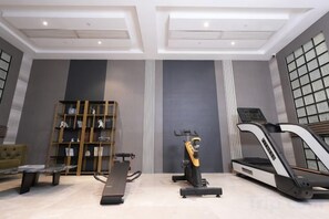 A gym with exercise equipment, a treadmill, and a stationary bike. - McQueen Hotel (Dongguan)