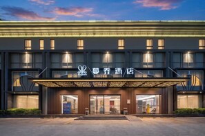 Een hotel met een moderne gevel, meerdere verdiepingen en een opvallende entree met een overkapping.