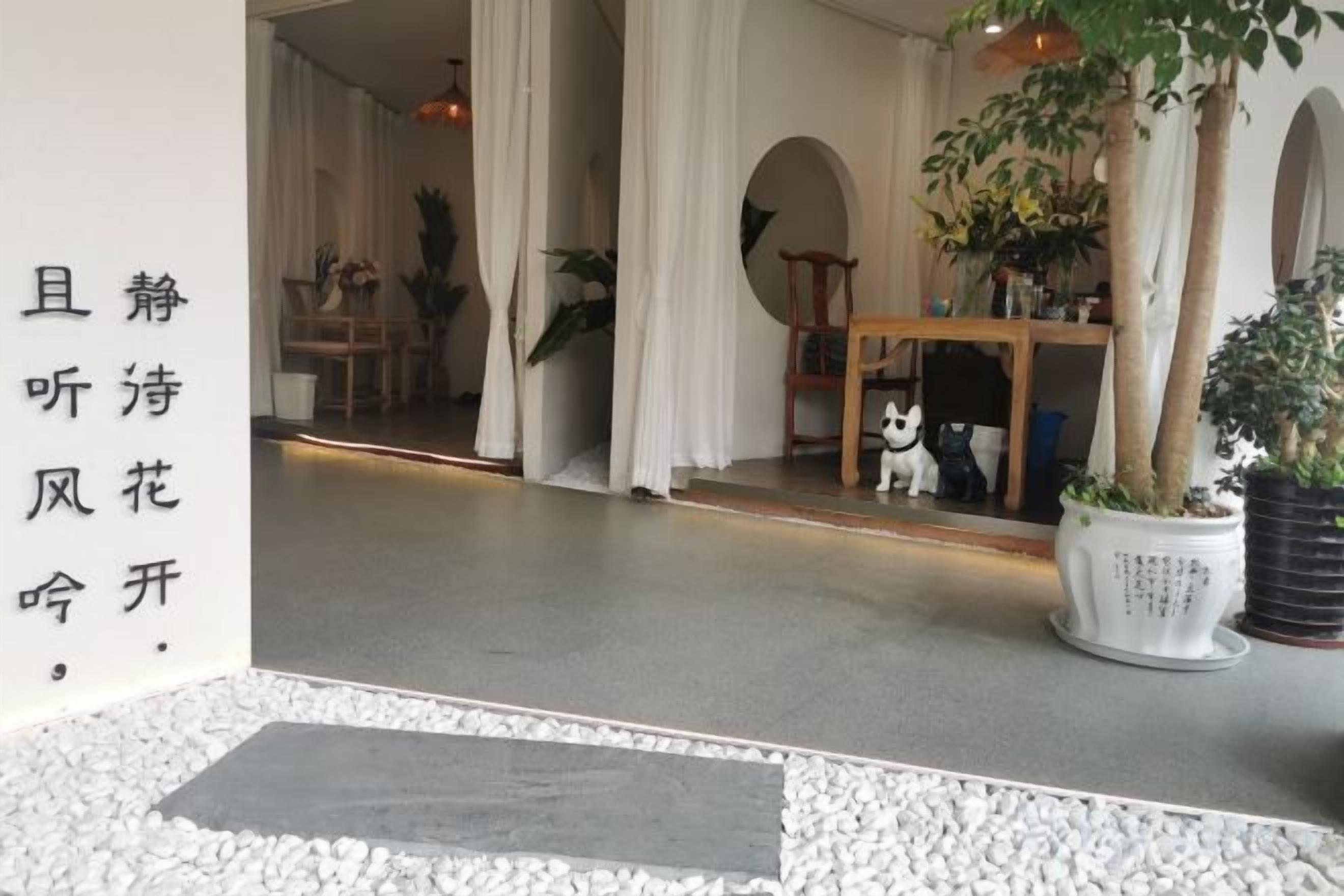 A room with a white floor, a potted plant, and a wooden table.