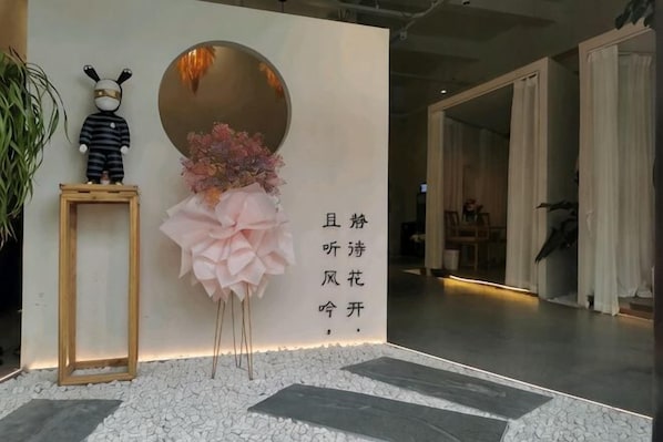 A reception area with a framed photo, a decorative flower arrangement, and a wall with text.