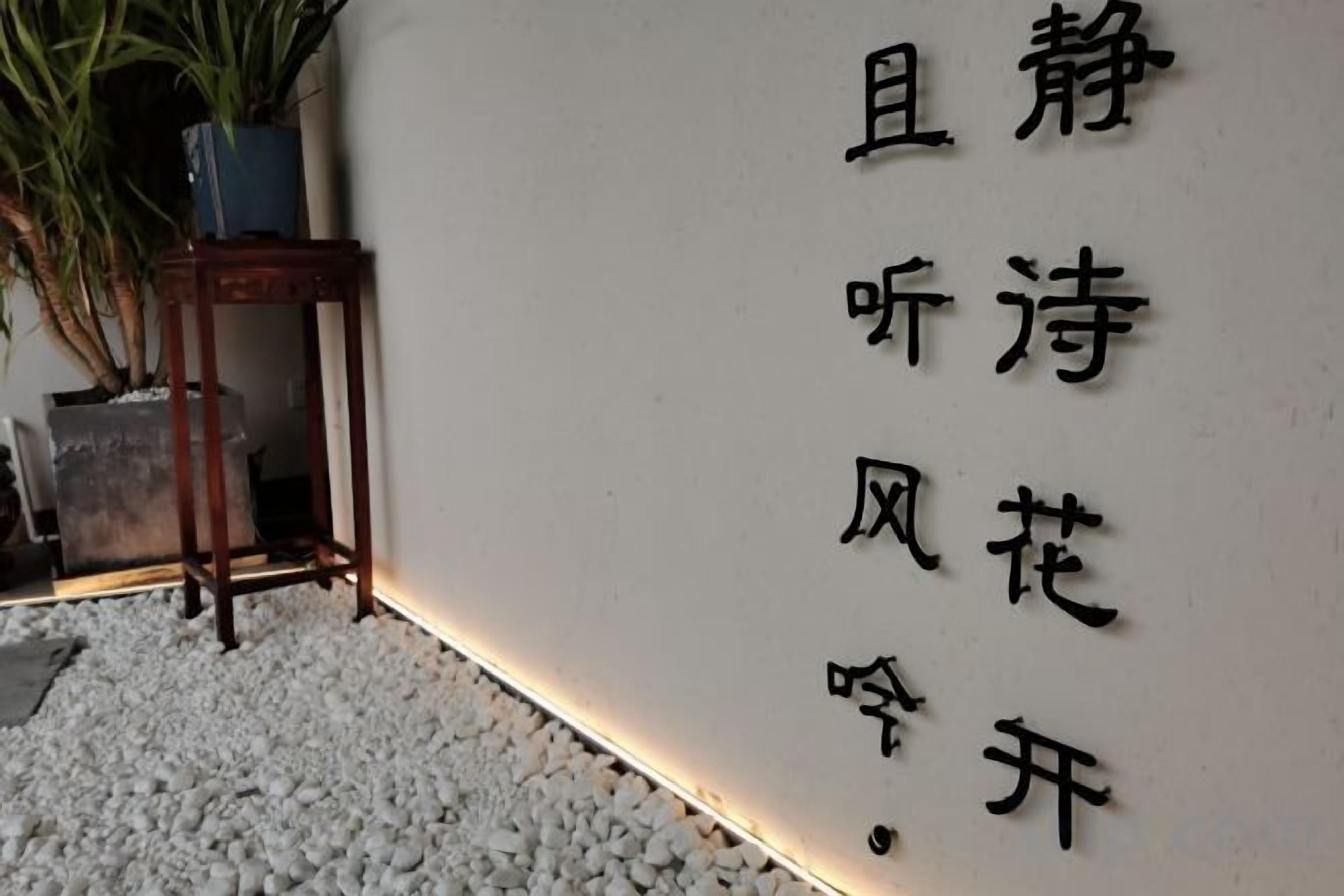 A wall with Chinese characters, a potted plant, and a small table.