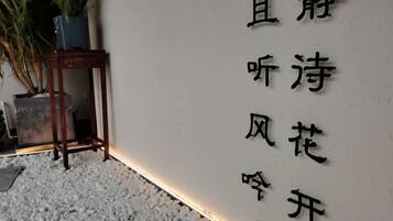 A wall with Chinese characters, a potted plant, and a small table.