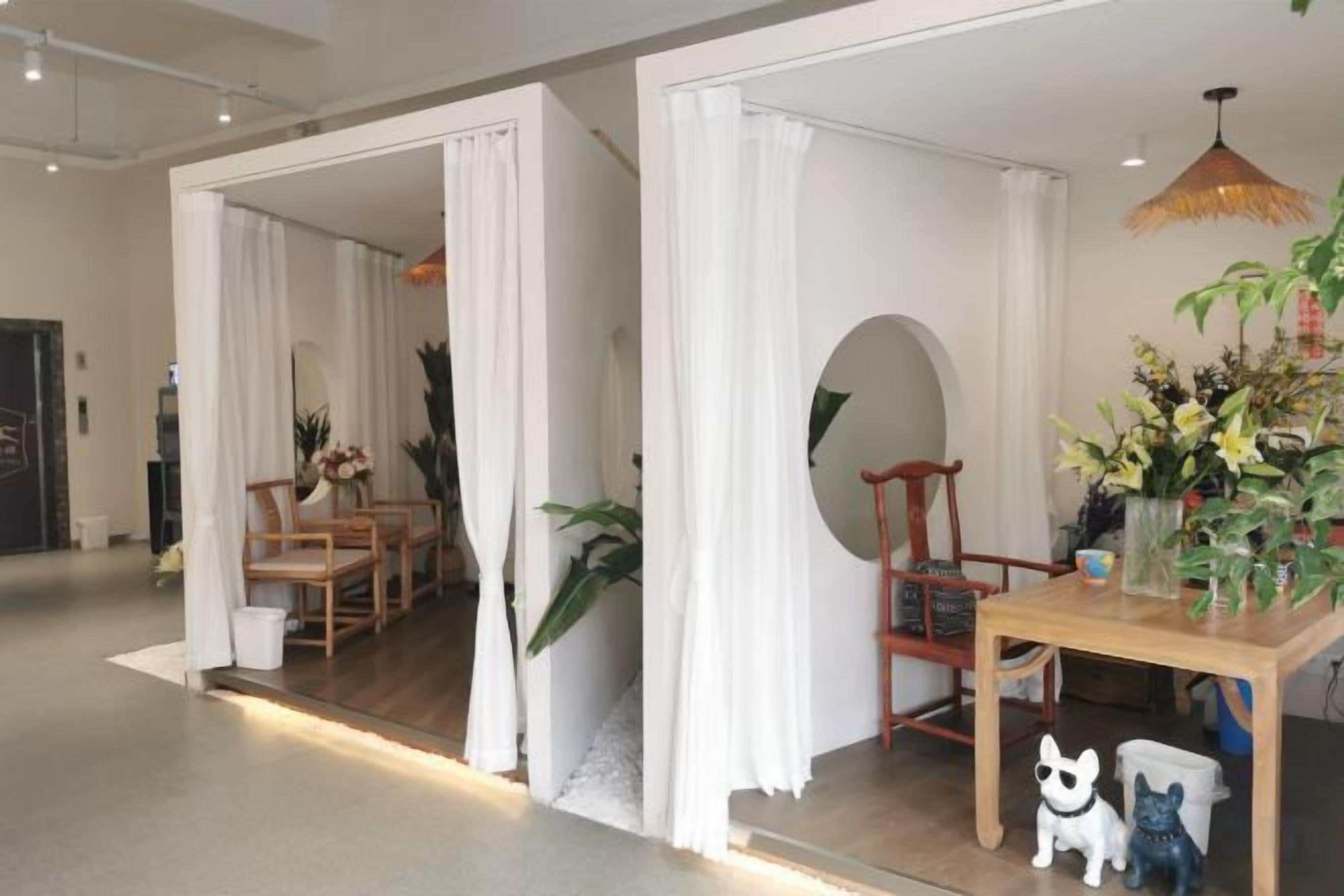 Een kamer met een houten eettafel, stoelen, een wit gordijn en een hanglamp.