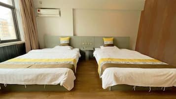 Habitación de hotel con dos camas, una ventana con cortinas, un equipo de aire acondicionado y una pared de madera.
