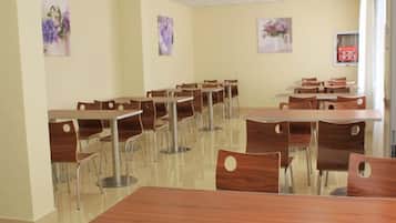 A dining area with multiple tables and chairs, arranged in rows.
