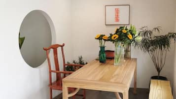Una mesa de comedor de madera con sillas, un florero con flores, un cuadro en la pared y una planta en maceta.