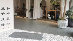 A room with a white floor, a wooden cabinet, a potted plant, and a small dog statue. - Yuting Express Hotel (Hai'an)