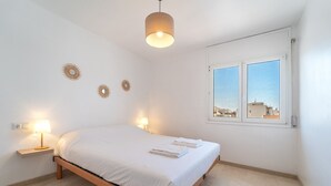 Une chambre à coucher avec un lit, des lampes de chevet et une fenêtre donnant sur la ville.