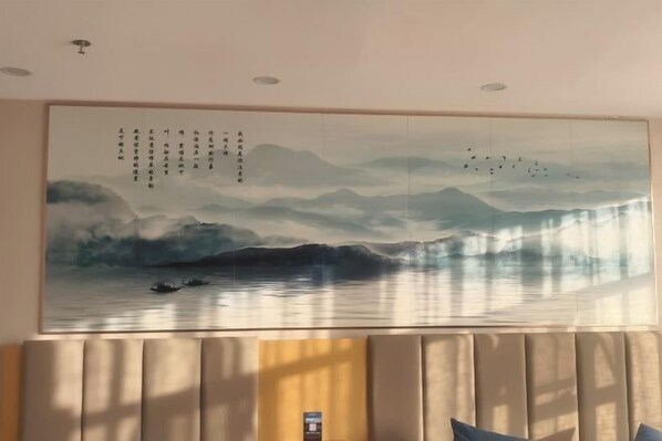 Una habitación con un cuadro grande de un paisaje montañoso y una masa de agua.