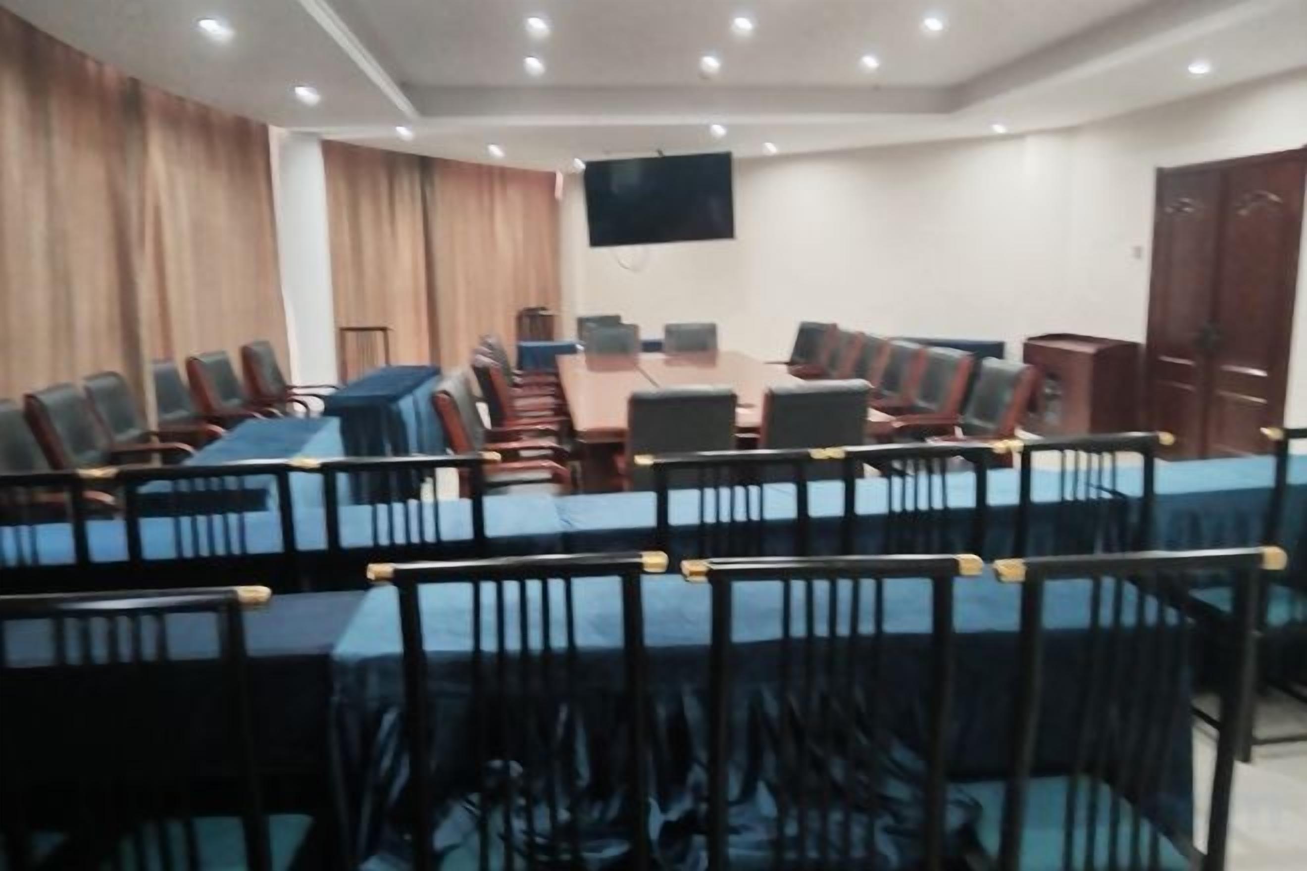 Una sala de conferencias con una mesa larga y sillas, un televisor de pantalla plana y una puerta de madera.