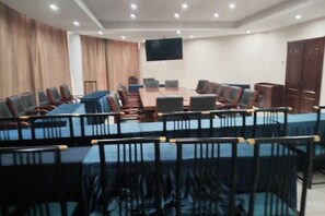 A conference room with a long table and chairs, a flat-screen TV, and a wooden door. - Yuanfang Hotel (Zhenglan Banner)