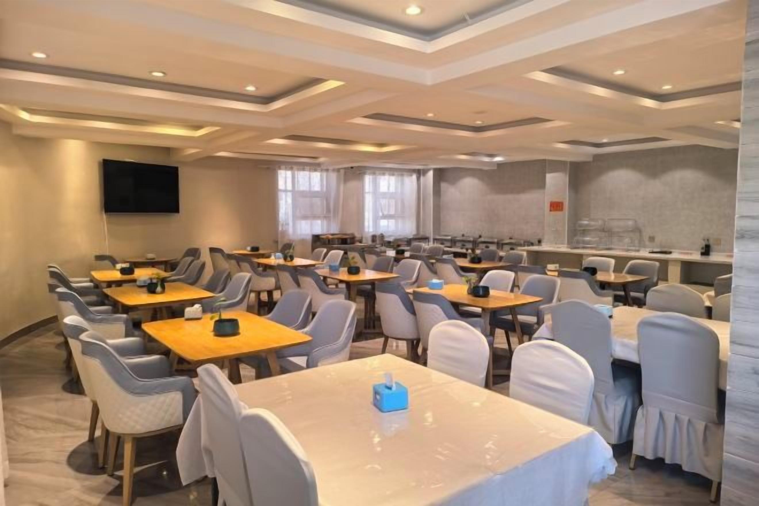 A conference room with multiple tables and chairs, a flat-screen TV on the wall, and a large window.