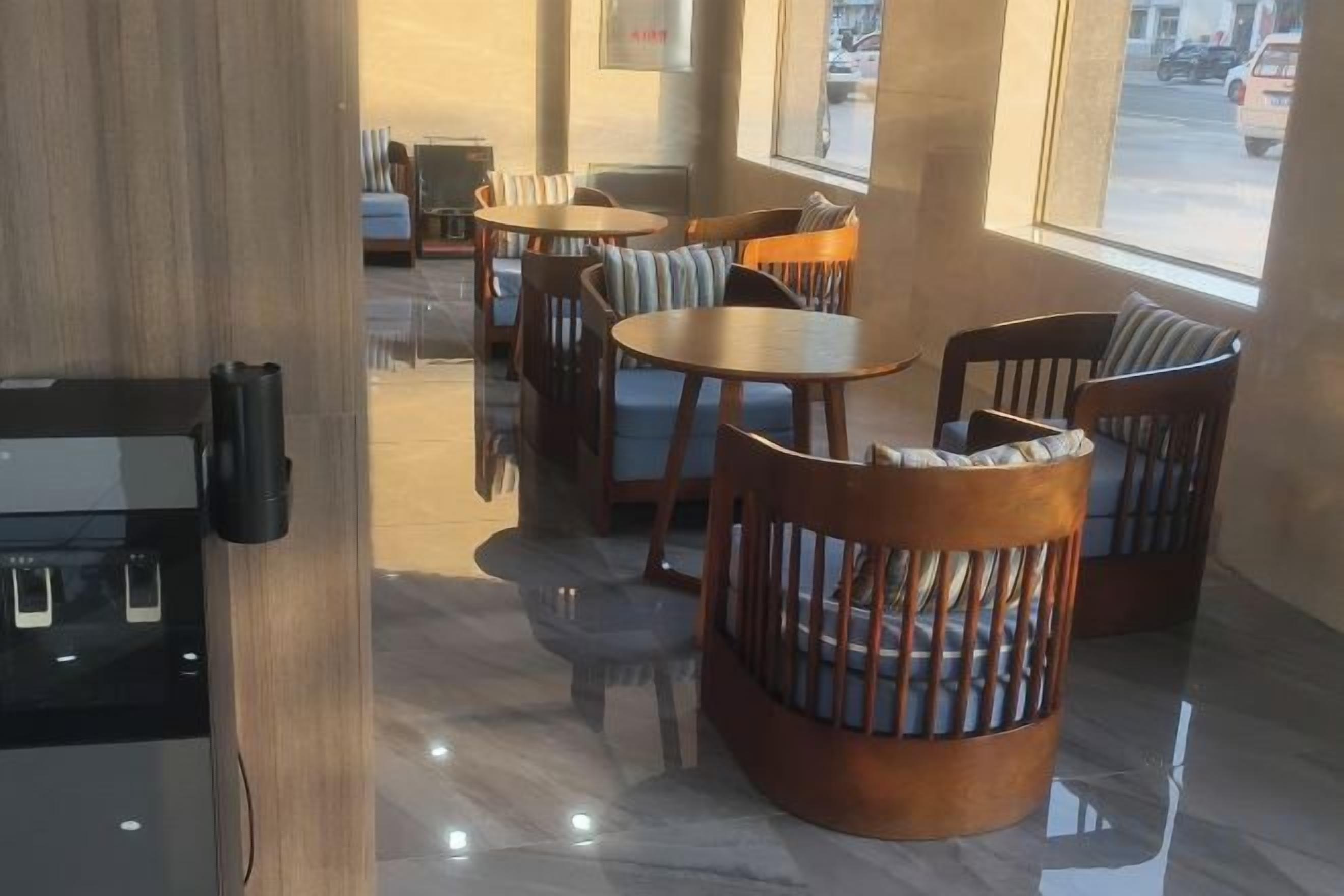 Interior de restaurante con mesas y sillas redondas, una barra de madera y vistas a través del ventanal.