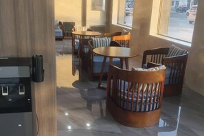 Interior de restaurante con mesas y sillas redondas, una barra de madera y vistas a través del ventanal.