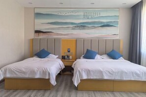 Una habitación doble con dos camas, un cuadro sobre las camas y un cabecero de madera.