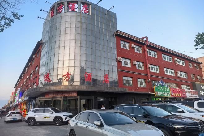 Un edificio de varios pisos con fachada curva, múltiples ventanales y diversa señalización.