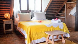 A cozy bedroom with a wooden bed, a bedside lamp, and a small wooden stool. - GREAT HOUSE BY MANAEVA LODGE (Moorea-Maiao)