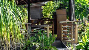 A covered outdoor area with wooden furniture, potted plants, and a rustic design. - GREAT HOUSE BY MANAEVA LODGE (Moorea-Maiao)