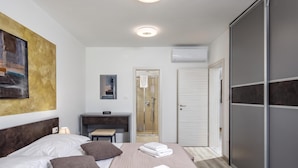 Una habitación de hotel con cama, mesita de noche, escritorio, ducha y armario.