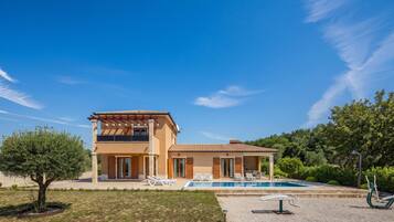 Uma casa de dois andares com piscina, área de estar externa e um jardim bem cuidado.