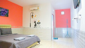 A hotel room with a bed, a wall-mounted air conditioner, a shower area, and a tiled floor.