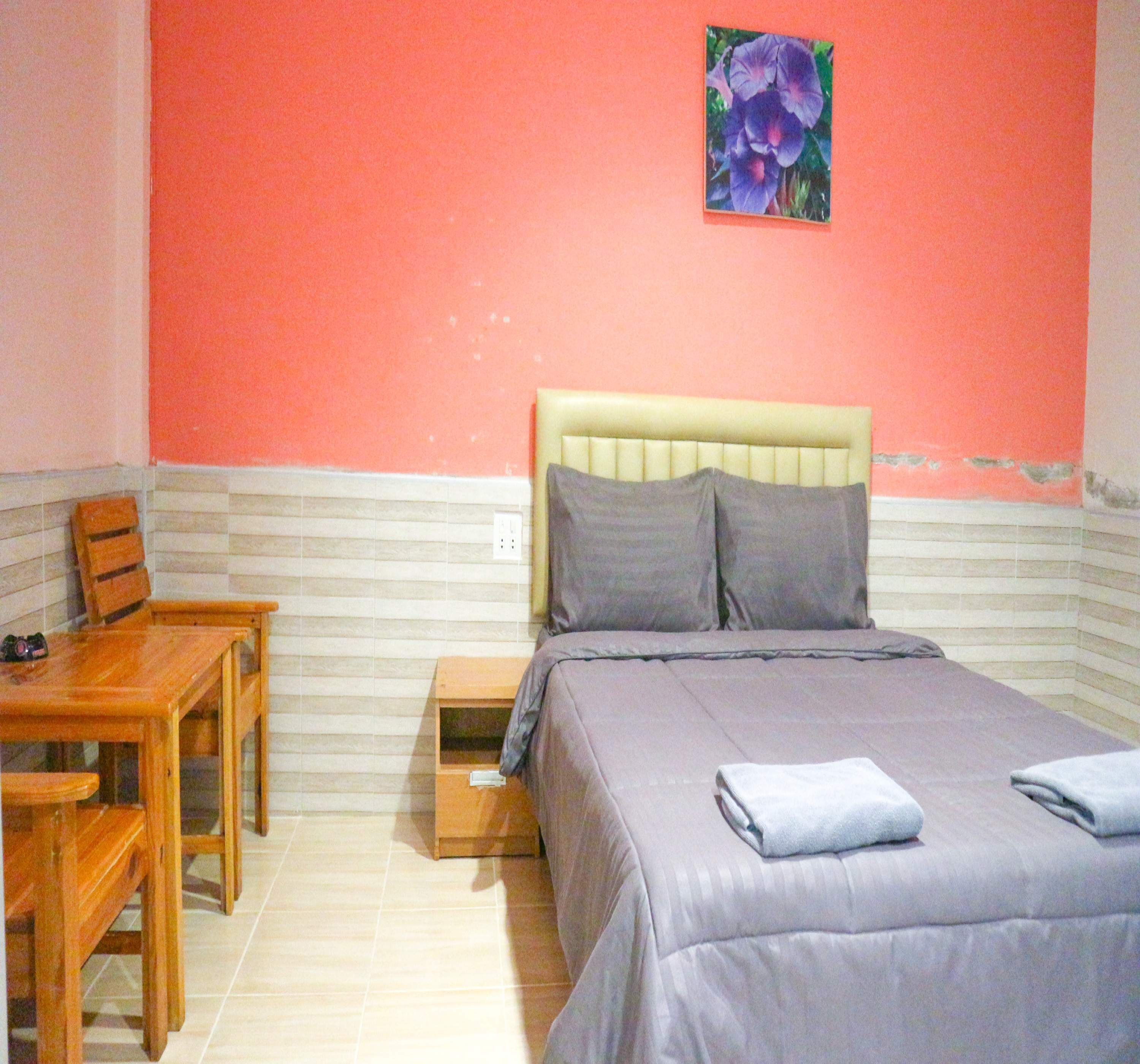 Un dormitorio con cama, mesita de noche y una silla.