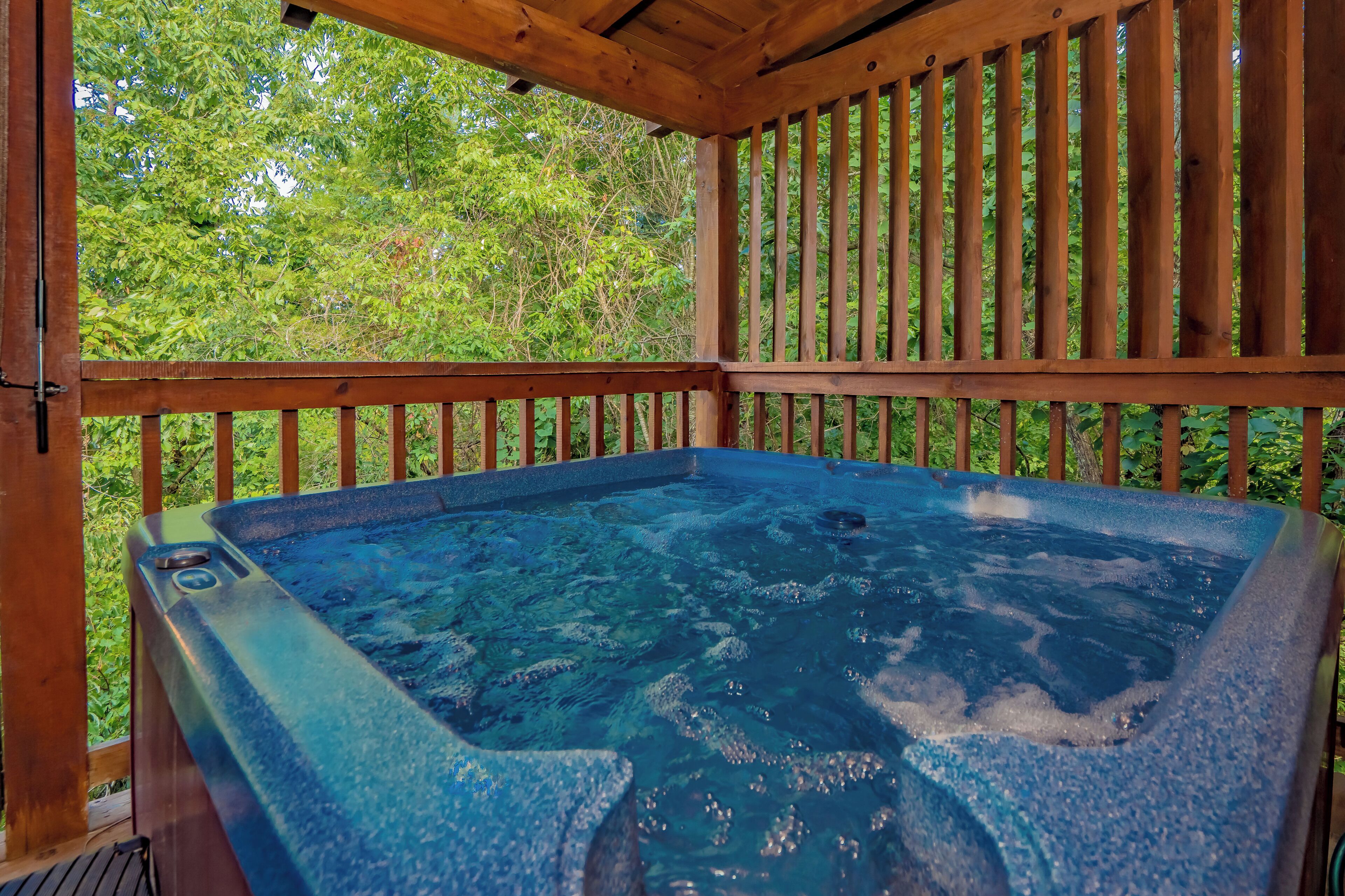 Un bain à remous installé sur une terrasse en bois, offrant une vue sur une végétation luxuriante.